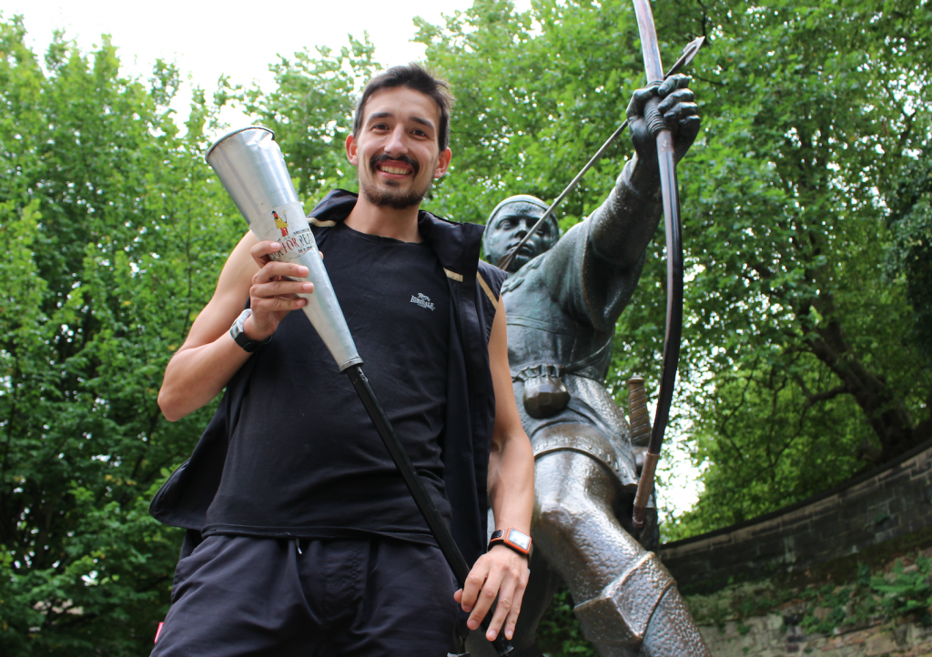 Adam Holland holds the Kenya Peace Torch beside the Robin Hood statue at Nottingham Castle, having won the 2016 Robin Hood Marathon. He is set to be the only athlete completing the 1,000km Kenya Peace Torch Relay.